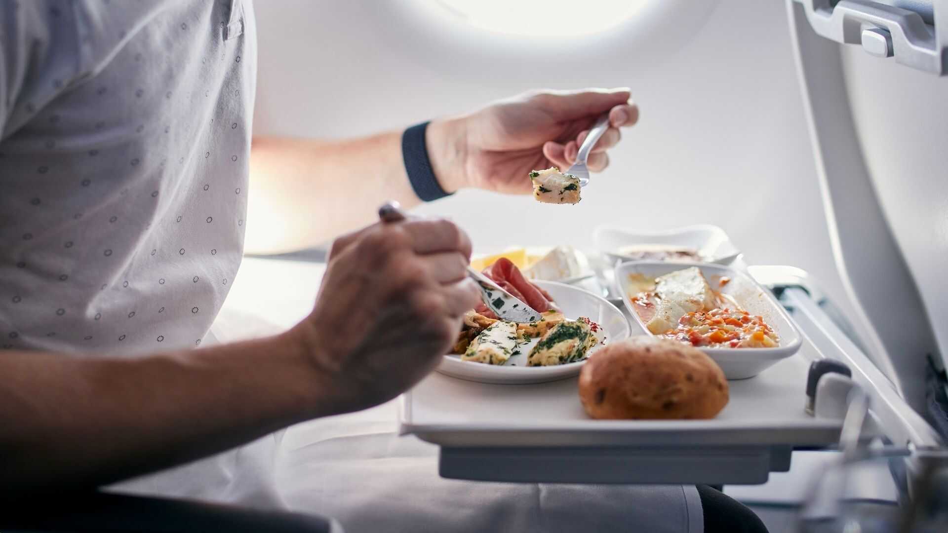 Passenger enjoying a gourmet meal aboard a customized commercial group charter flight.